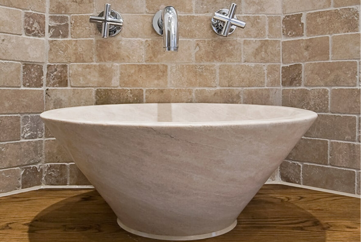 Glänzende Armatur vor dunkler Natursteinplatte mit Musterung