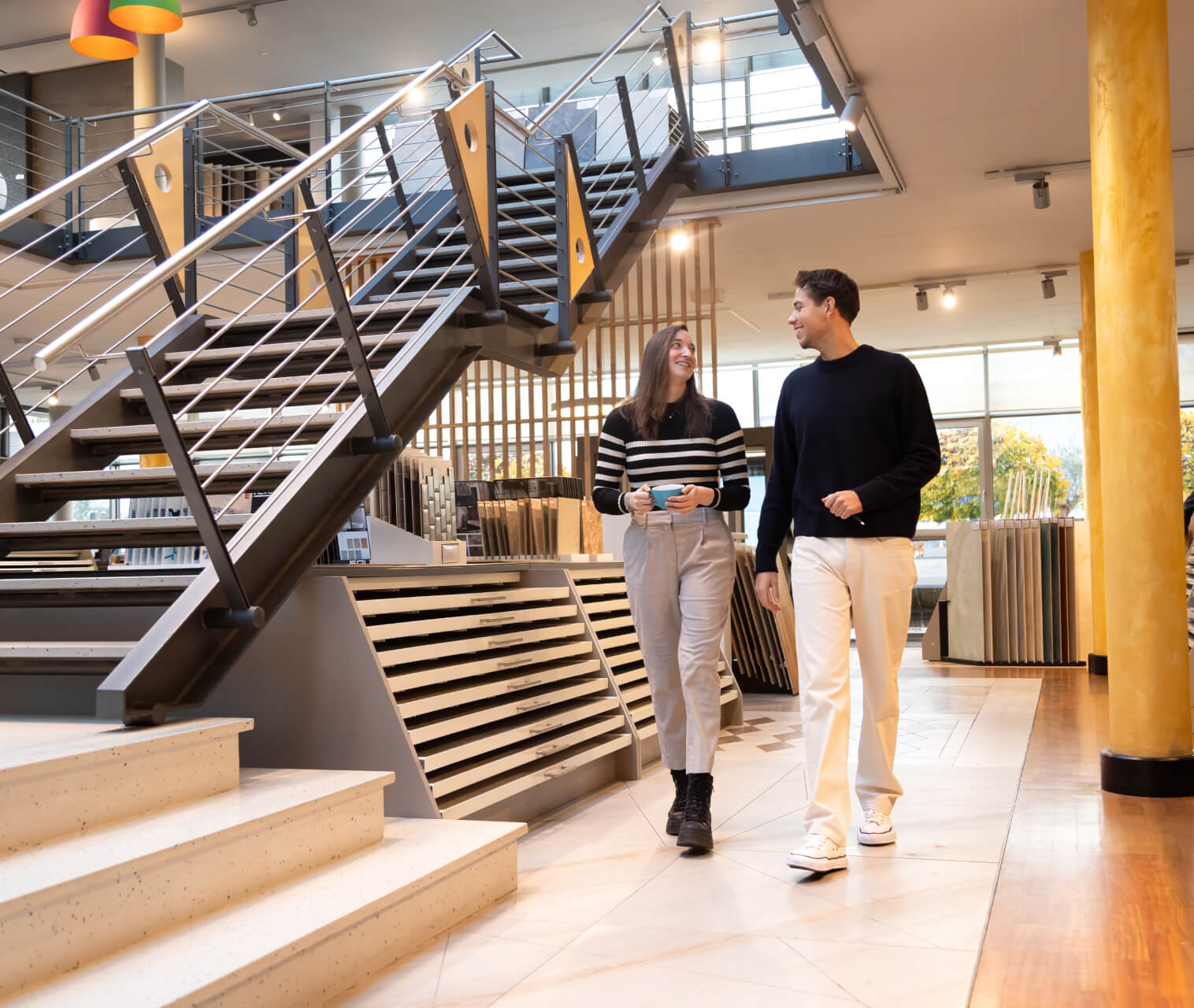 Zwei Personen gehen eine Treppe im Showroom hinunter und unterhalten sich