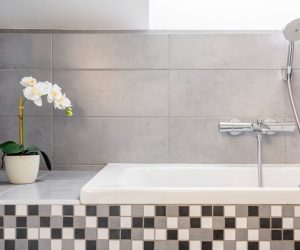 Badewanne vor grauen Wandfliesen mit kariertem Sockel