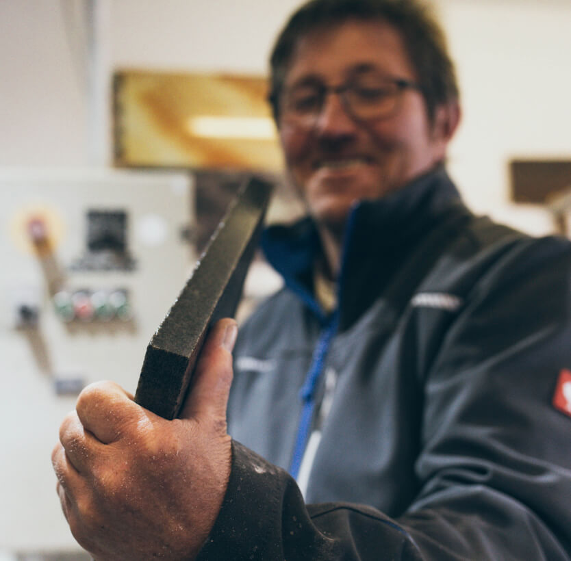 Mitarbeiter zeigt ein Werkzeug oder Produkt und lächelt dabei