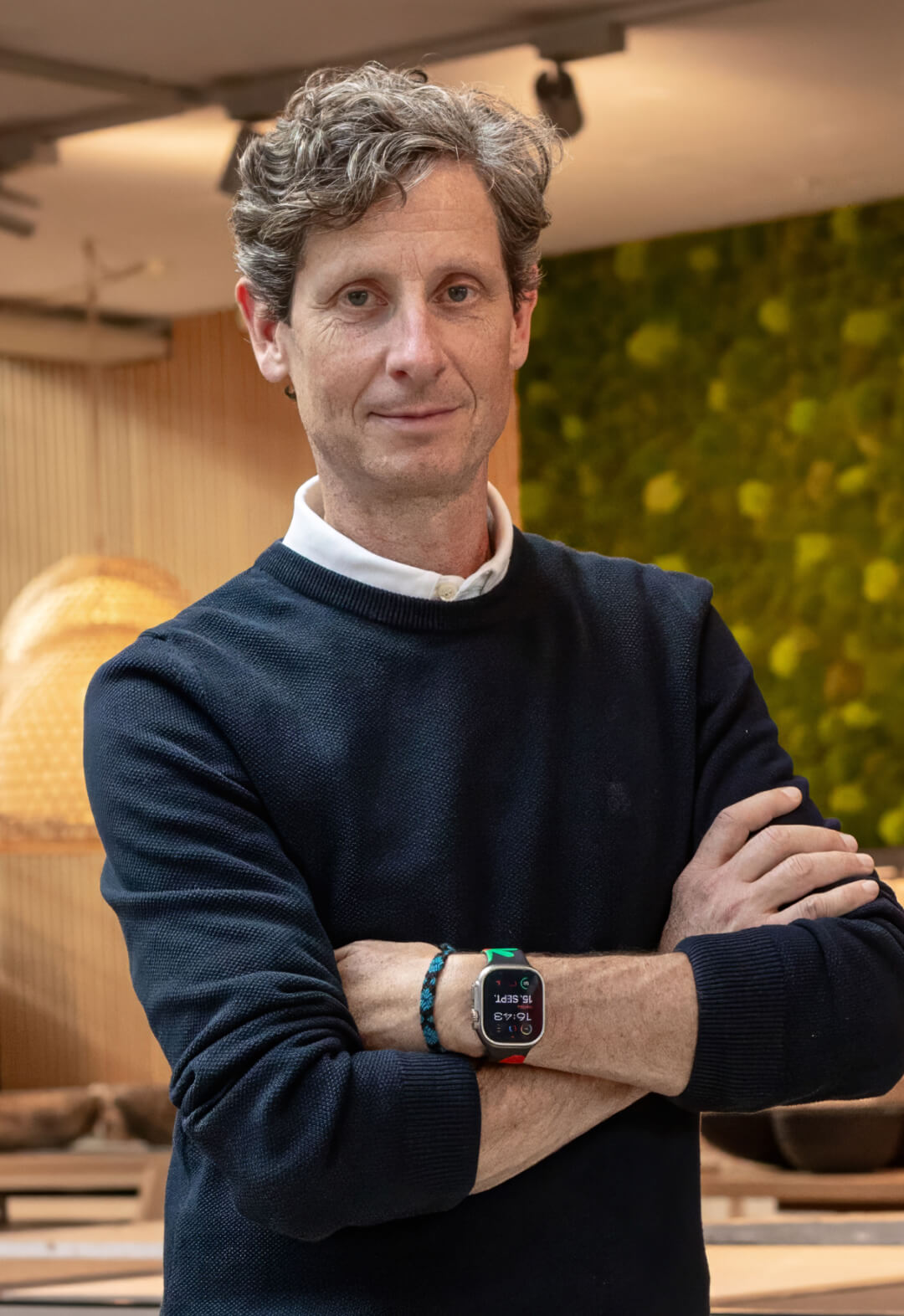 Mann mit verschränkten Armen vor begrüntem Hintergrund