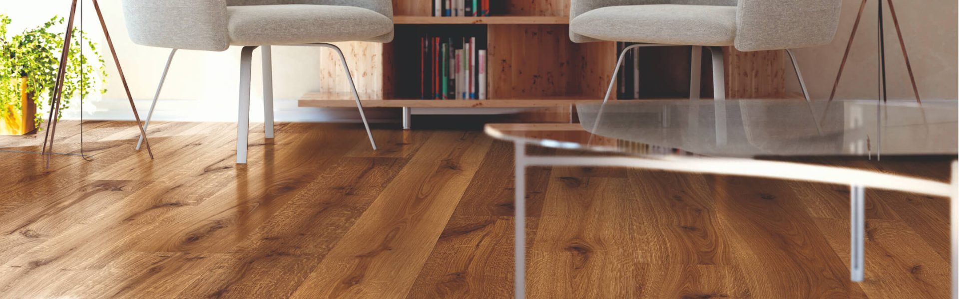 Wohnzimmer mit hellem Holzboden, gemütlichen Sesseln und Bücherregal