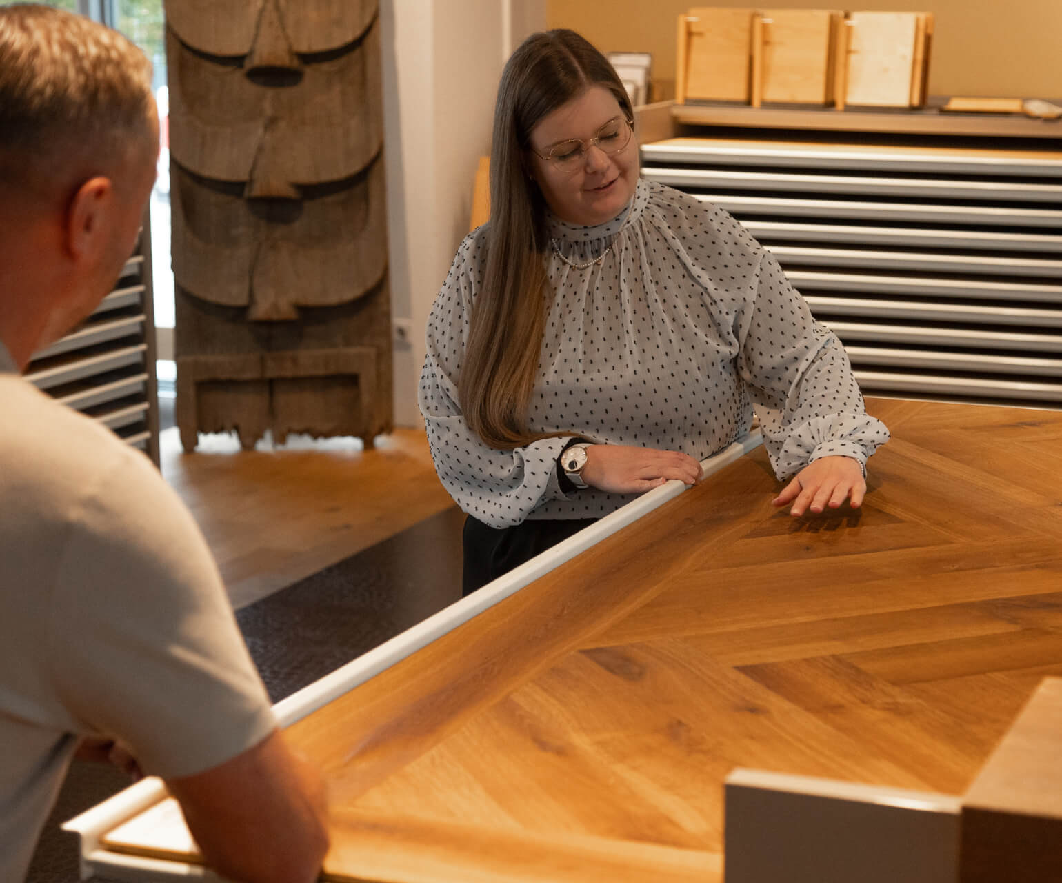 Frau betrachtet Holzmusterschienen und vergleicht Bodenbeläge