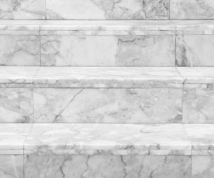 Freistehende Naturstein-Badewanne vor beiger Fliesenwand