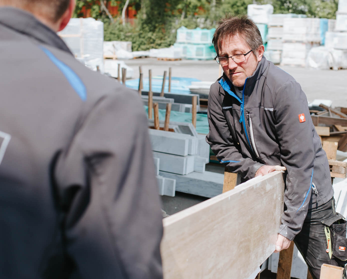 Mitarbeiter transportieren große Steinplatten im Außenbereich