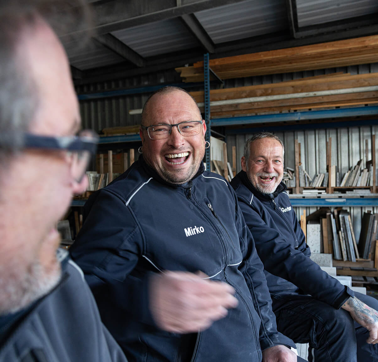 Zwei Mitarbeiter in Arbeitskleidung lachen während eines Gesprächs