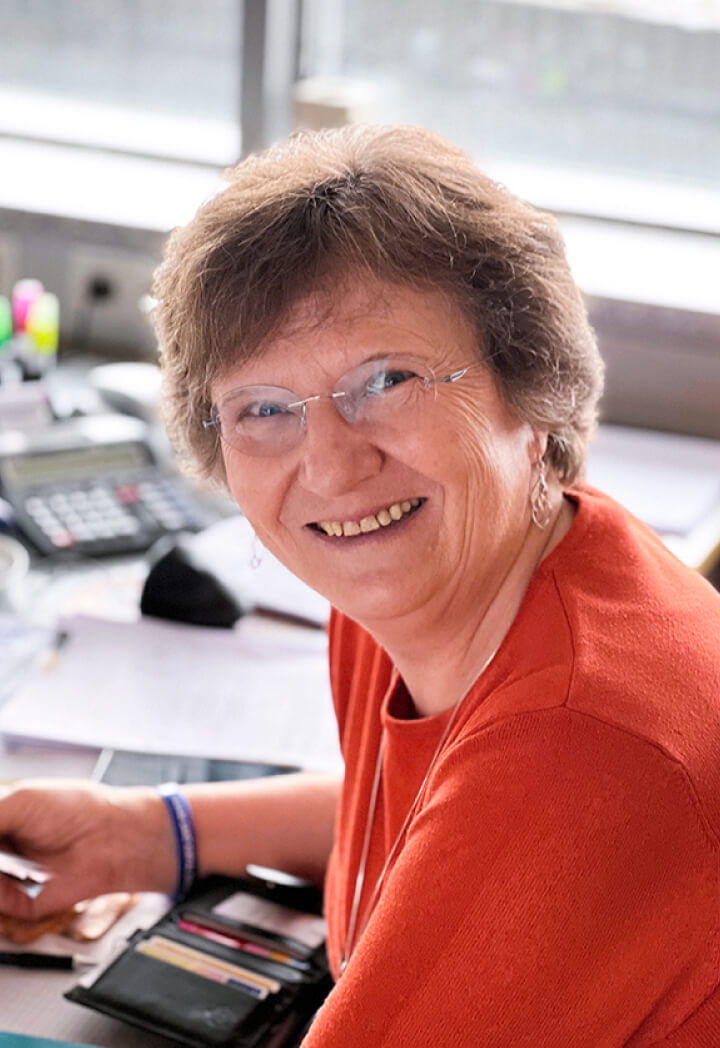 Frau am Schreibtisch mit Headset, freundlich lächelnd