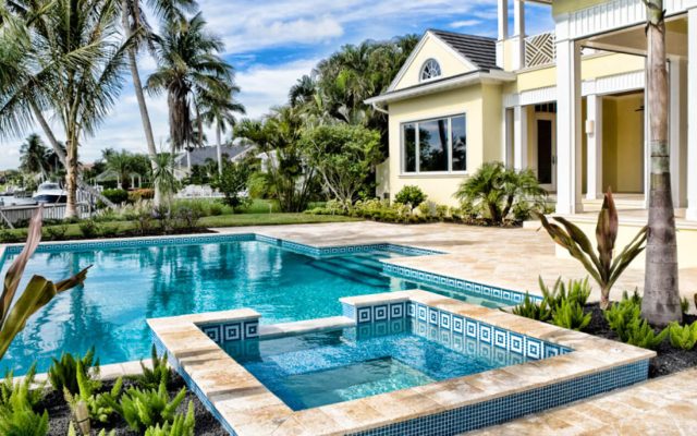 Poolbereich mit hellen Steinfliesen und kristallblauem Wasser