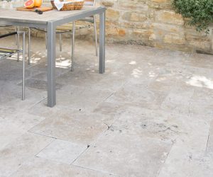 Terrasse mit hellen Natursteinfliesen und Tisch im Außenbereich