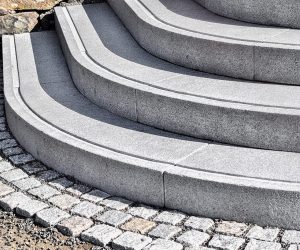 Halbkreisförmige Außentreppe aus grauem Naturstein mit Pflastersteinen