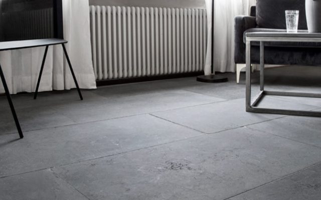 Graue Bodenfliesen in einem hellen Raum mit Stuhl und Heizkörper
