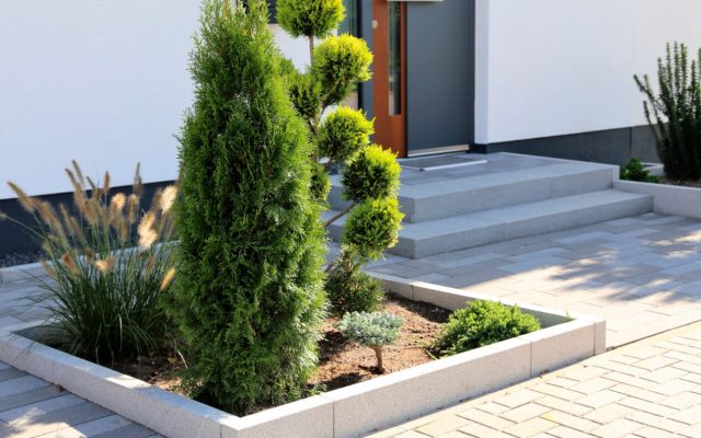 Eingangsbereich eines Hauses mit Natursteinplatten und frisch gepflanzten Sträuchern
