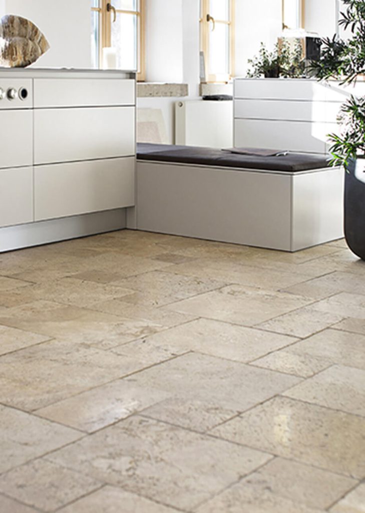 Helle Natursteinfliesen in einer modernen Küche mit weißen Fronten