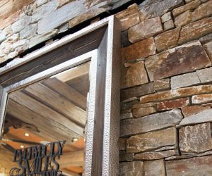 Natursteinwand mit Spiegel und rustikalem Holzrahmen