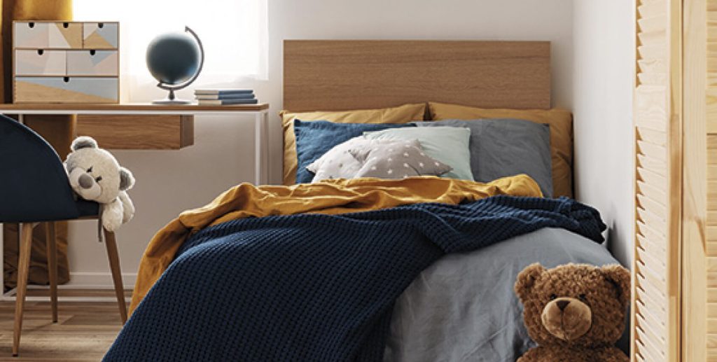 Schlafzimmer mit Holzbett, blauer Bettwäsche und warmem Holzboden