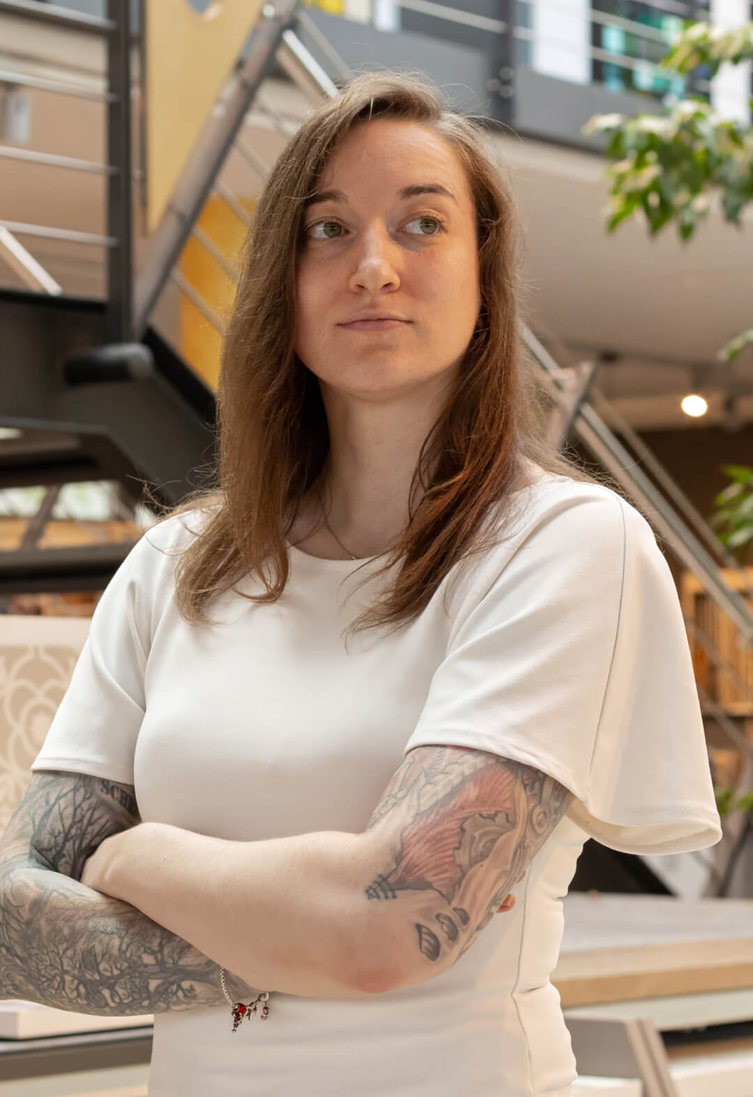 Frau mit Tätowierungen und weißem Shirt mit verschränkten Armen