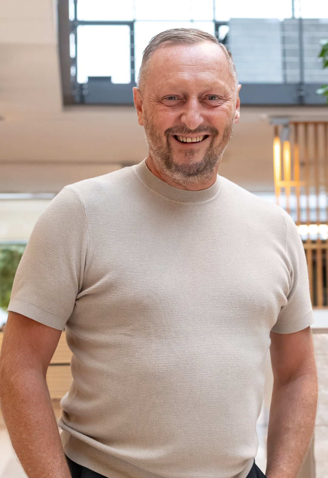 Lächelnder Mann im beigen Shirt in einer Ausstellung