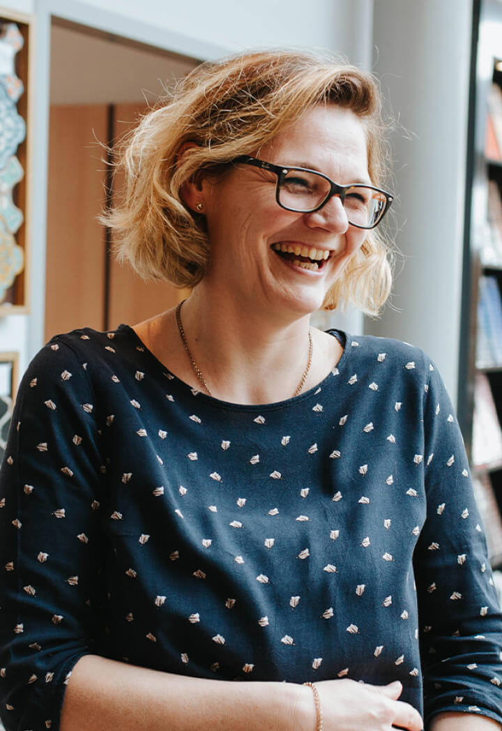 Lächelnde Frau mit Brille in einem modernen Innenraum