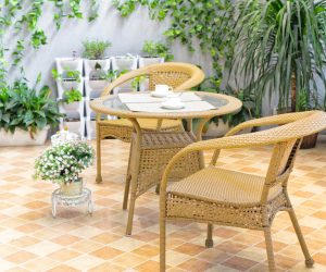 Outdoor-Sitzbereich mit Korbstühlen und kleinem runden Tisch auf Fliesenboden