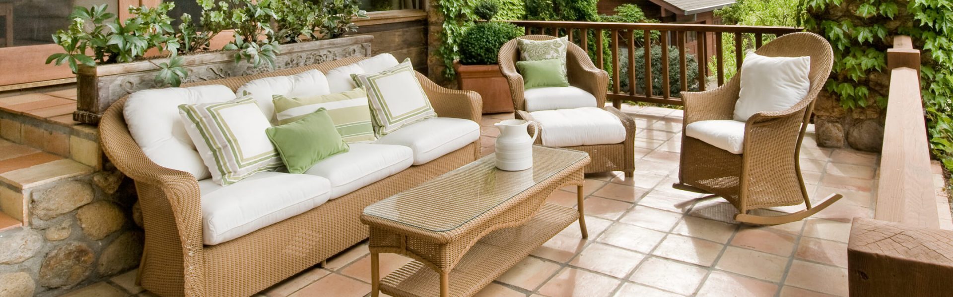 Gemütliche Terrasse mit Rattan-Sofa, Kissen und Holztisch