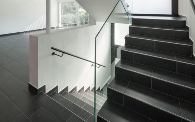 Schwarze Treppe mit Glasgeländer in modernem Innenraum