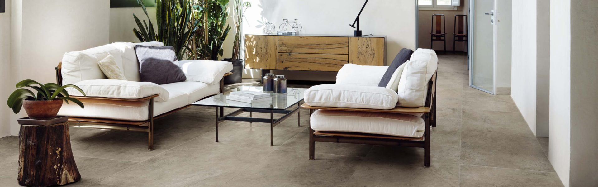 Modernes Wohnzimmer mit hellen Sofas, großen Pflanzen und Holzdetails